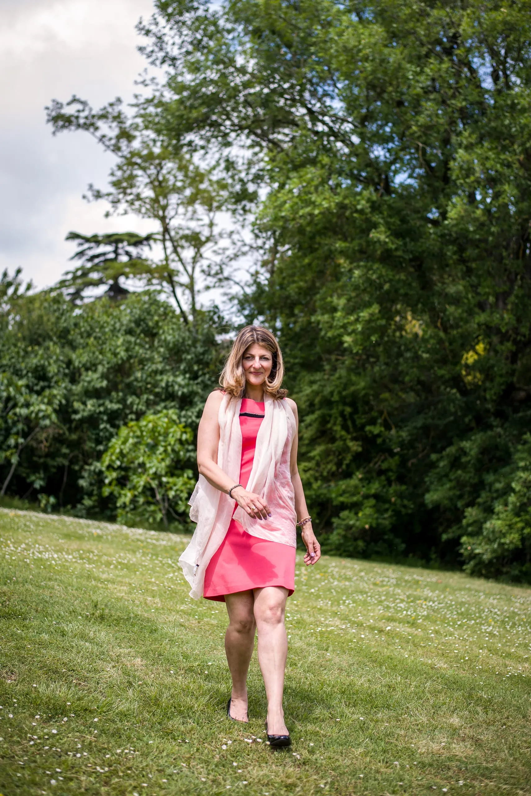 Gabrielle Ladevant, coach et professeure de yoga, souriante et détendue dans un jardin verdoyant, robe corail.