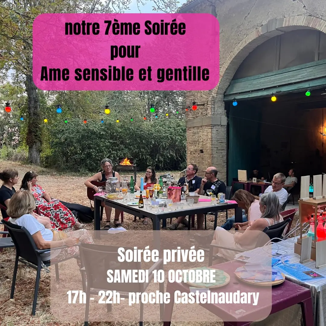 Participants réunis autour d'une table sous des lampions lors d'une soirée âmes sensibles